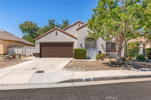 1083 Mill Iron Way, San Jacinto, CA 92583 - mediterranean / spanish home featuring stucco siding, a garage, concrete driveway, a tile roof, and a gate