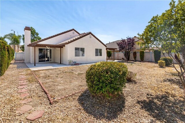 1083 Mill Iron Way, San Jacinto, CA 92583 - back of property featuring stucco siding, a patio, a fenced backyard, and a chimney