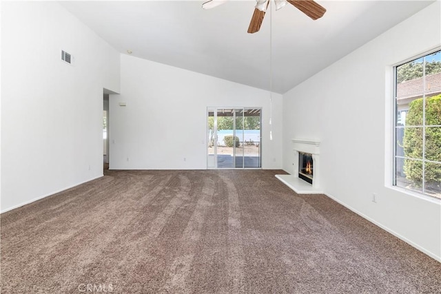 1083 Mill Iron Way, San Jacinto, CA 92583 - unfurnished living room featuring carpet, ceiling fan, plenty of natural light, a glass covered fireplace, and high vaulted ceiling