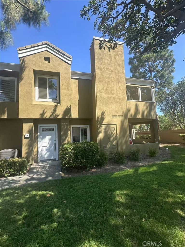14 Scripps Aisle Unit 173, Irvine, CA 92612 - view of front facade featuring stucco siding, a front lawn, and a chimney