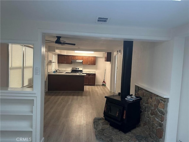 2023 Jewell Ln, Redding, CA 96001 - kitchen featuring stainless steel range with electric stovetop, wood finished floors, a ceiling fan, a wood stove, and light countertops