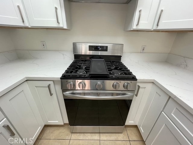 1415 El Sereno Ave Unit 4, Pasadena, CA 91103 - kitchen with stainless steel gas stove, white cabinetry, light tile patterned floors, and light stone countertops