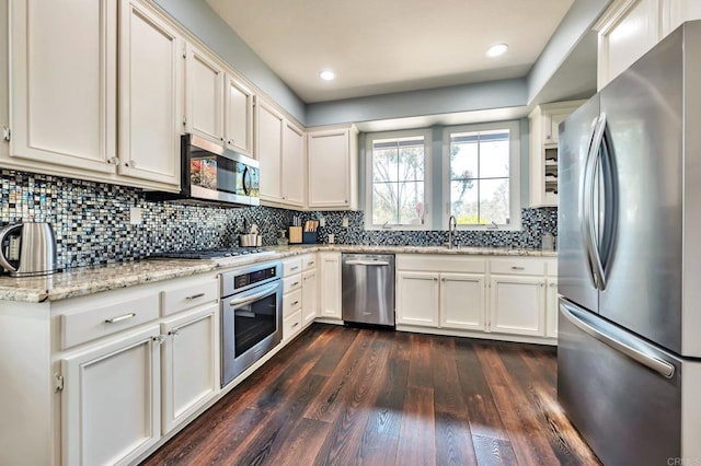 6847 Adolphia Dr, Carlsbad, CA 92011 - kitchen with appliances with stainless steel finishes, dark wood-style floors, tasteful backsplash, light stone countertops, and white cabinets