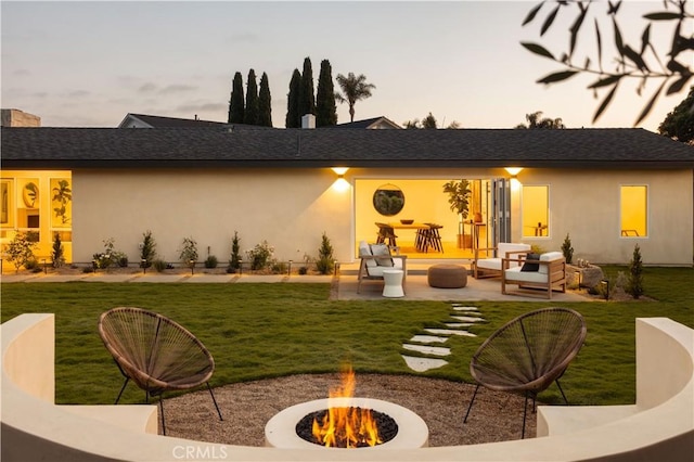 3499 San Rafael Cir, Costa Mesa, CA 92626 - back of property at dusk featuring a patio, stucco siding, a lawn, and an outdoor living space with a fire pit