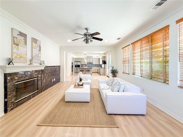 43097 Calle Camellia, Temecula, CA 92592 - living room featuring light wood-type flooring, crown molding, ceiling fan, a high end fireplace, and recessed lighting