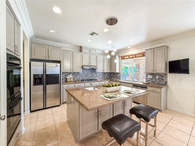 43097 Calle Camellia, Temecula, CA 92592 - kitchen with appliances with stainless steel finishes, backsplash, under cabinet range hood, a kitchen island with sink, and ornamental molding