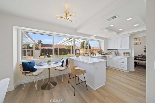 2143 Westminster Dr, Palmdale, CA 93550 - kitchen featuring a chandelier, light wood-style floors, white cabinets, a peninsula, and a breakfast bar