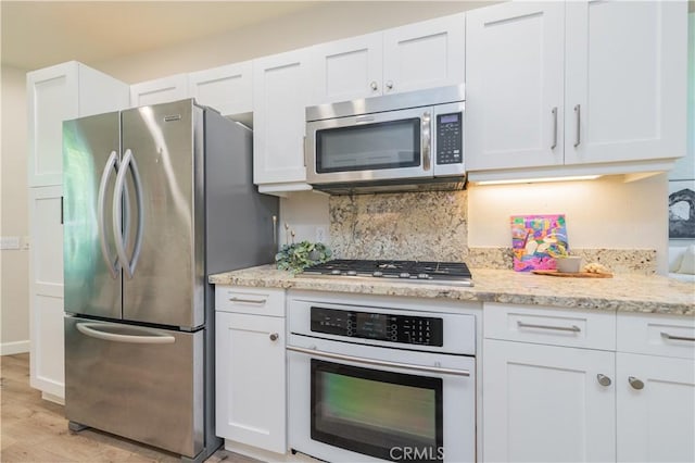 5 Bretagne, Newport Coast, CA 92657 - kitchen with stainless steel appliances, white cabinetry, light wood finished floors, tasteful backsplash, and light stone counters