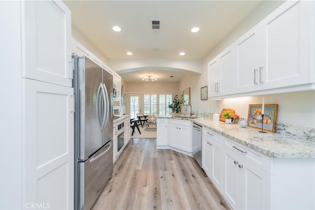 5 Bretagne, Newport Coast, CA 92657 - kitchen featuring stainless steel appliances, arched walkways, a peninsula, white cabinetry, and light wood-style floors
