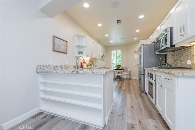 5 Bretagne, Newport Coast, CA 92657 - kitchen with open shelves, stainless steel appliances, white cabinetry, light wood finished floors, and recessed lighting