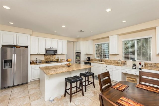 31578 Waterfall Way, Murrieta, CA 92563 - kitchen featuring appliances with stainless steel finishes, a kitchen breakfast bar, white cabinetry, a kitchen island, and light stone counters