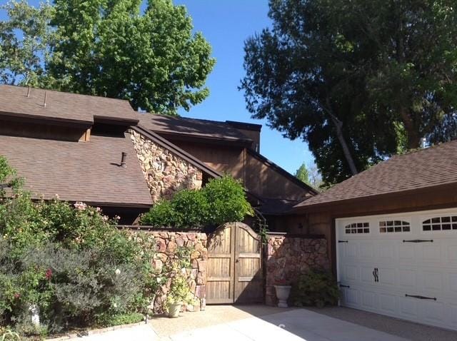 31842 Via Oso, Coto De Caza, CA 92679 - mid-century modern home with stone siding, a gate, a garage, a shingled roof, and driveway