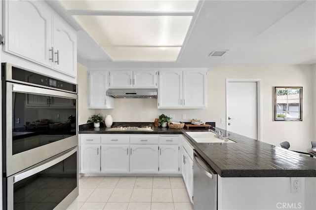 1061 Regis Way, Tustin, CA 92780 - kitchen with appliances with stainless steel finishes, dark countertops, a peninsula, and under cabinet range hood