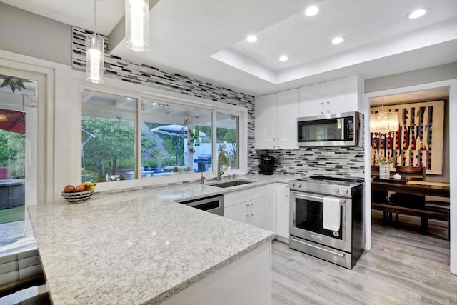 12395 Filera Rd, San Diego, CA 92128 - kitchen with appliances with stainless steel finishes, a peninsula, white cabinets, light wood-style flooring, and recessed lighting