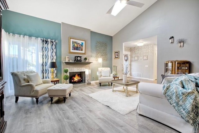 12395 Filera Rd, San Diego, CA 92128 - living room with high vaulted ceiling, wood finished floors, a tile fireplace, a ceiling fan, and a skylight