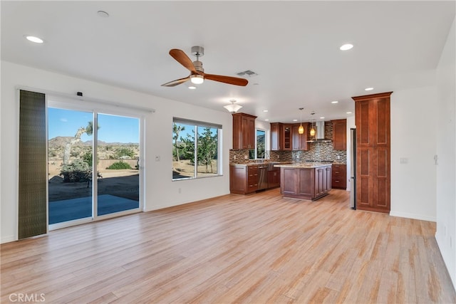 7765 Elwood St, Joshua Tree, CA 92252 - kitchen with wall chimney exhaust hood, a kitchen island, light wood-type flooring, decorative backsplash, and ceiling fan