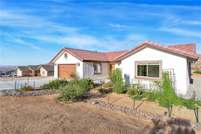 7765 Elwood St, Joshua Tree, CA 92252 - ranch-style home featuring a tiled roof, concrete driveway, stucco siding, and an attached garage