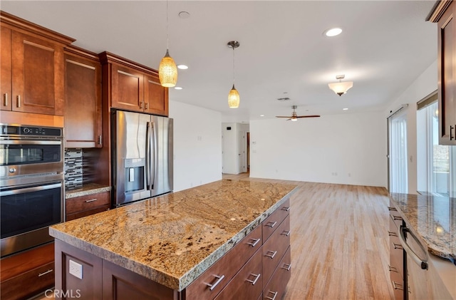7765 Elwood St, Joshua Tree, CA 92252 - kitchen with appliances with stainless steel finishes, a ceiling fan, pendant lighting, light wood-style flooring, and a center island