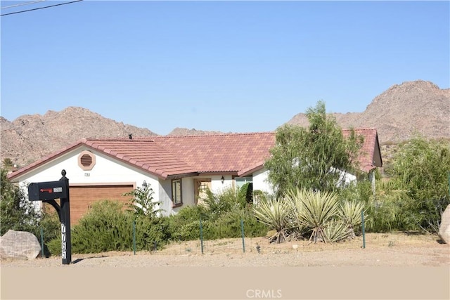 7765 Elwood St, Joshua Tree, CA 92252 - view of front of property featuring a tile roof, a mountain view, an attached garage, and stucco siding