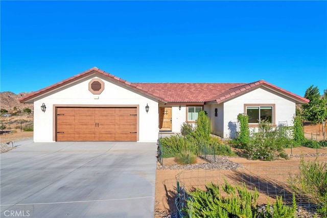 7765 Elwood St, Joshua Tree, CA 92252 - view of front of house with stucco siding, a tile roof, concrete driveway, and an attached garage