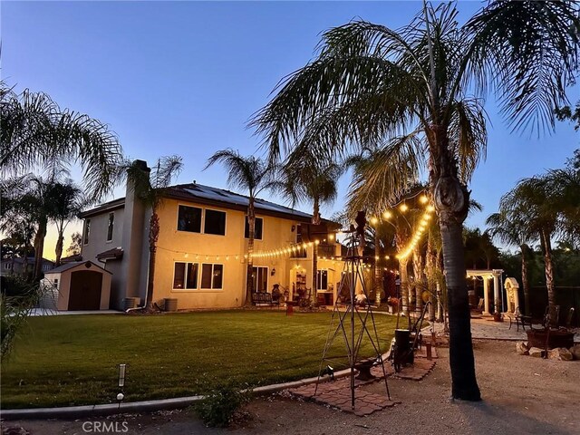 22760 Shadygrove Ct, Wildomar, CA 92595 - back of property featuring roof mounted solar panels, a storage shed, a chimney, a lawn, and stucco siding