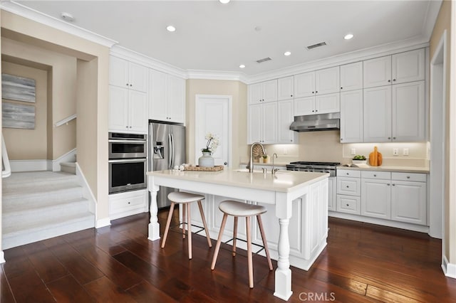 54 Sycamore Bnd, Irvine, CA 92620 - kitchen featuring under cabinet range hood, stainless steel appliances, a kitchen breakfast bar, dark wood finished floors, and recessed lighting