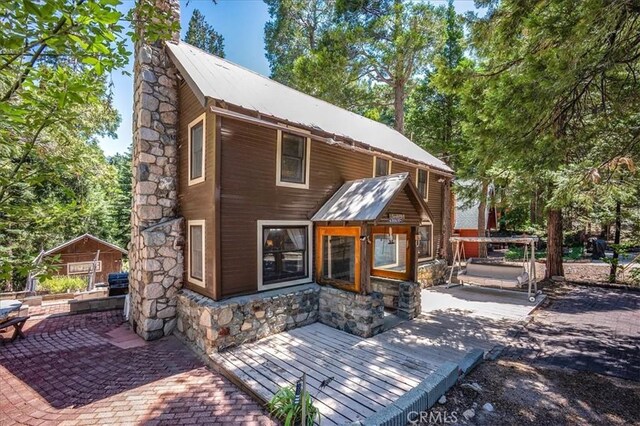 25837 Sunset Loop, Twin Peaks, CA 92391 - back of house with a chimney, stone siding, a metal roof, a deck, and a patio