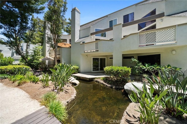 222 N Singingwood St Unit 9, Orange, CA 92869 - back of property with a garden pond, stucco siding, a chimney, and a balcony