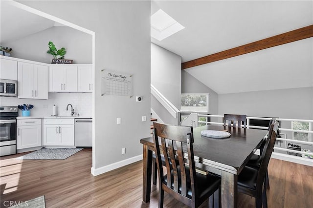 222 N Singingwood St Unit 9, Orange, CA 92869 - dining room featuring beam ceiling, a skylight, light wood-type flooring, and high vaulted ceiling