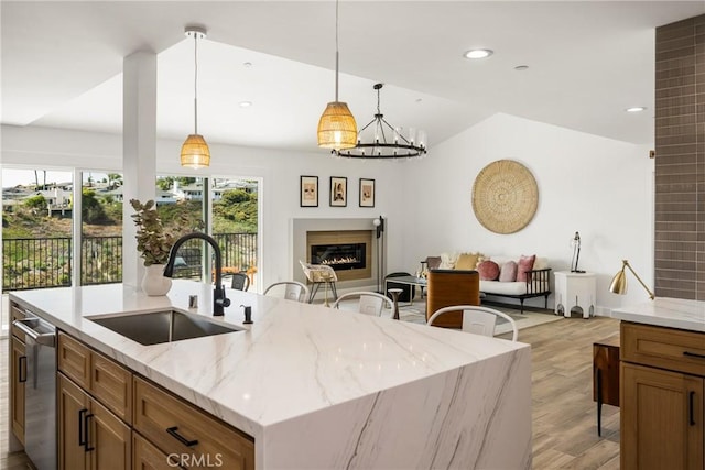 235 Via Ballena, San Clemente, CA 92672 - kitchen with light wood-type flooring, a center island with sink, decorative light fixtures, brown cabinetry, and a lit fireplace