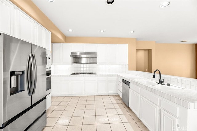 45422 Camino Monzon, Temecula, CA 92592 - kitchen with appliances with stainless steel finishes, tasteful backsplash, tile countertops, light tile patterned flooring, and a peninsula