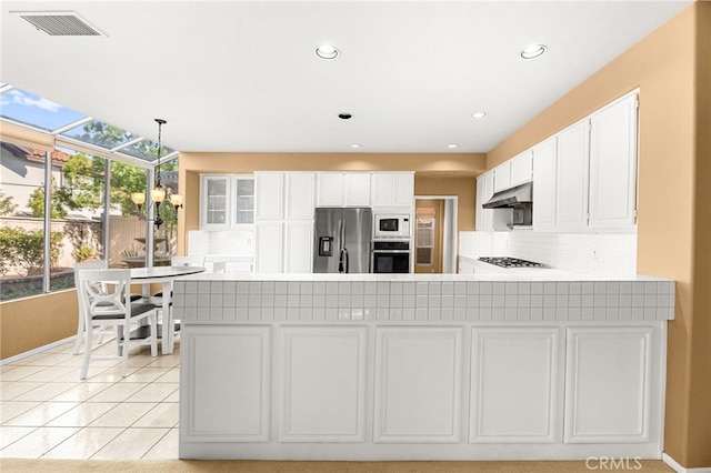 45422 Camino Monzon, Temecula, CA 92592 - kitchen with stainless steel appliances, under cabinet range hood, backsplash, light countertops, and white cabinetry