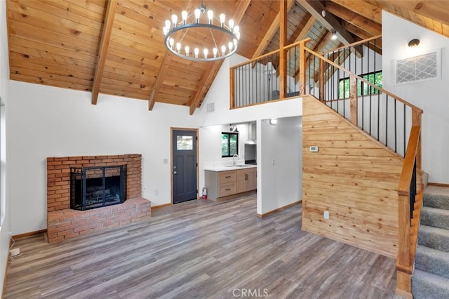 33198 Arrowbear Dr, Running Springs, CA 92382 - unfurnished living room featuring high vaulted ceiling, wood finished floors, a brick fireplace, a chandelier, and a wood ceiling with exposed beams