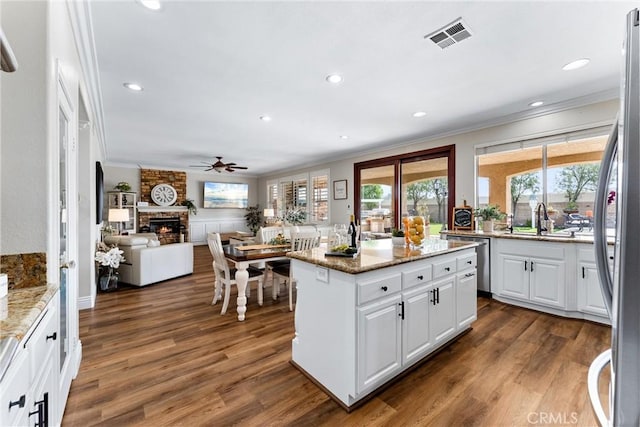 2571 Stetson Dr, Norco, CA 92860 - kitchen featuring crown molding, ceiling fan, white cabinetry, a large fireplace, and dark wood-style flooring
