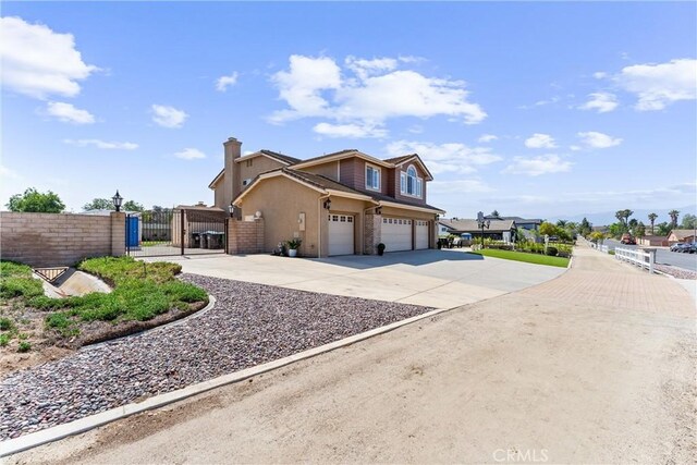 2571 Stetson Dr, Norco, CA 92860 - view of home's exterior featuring a gate, an attached garage, concrete driveway, a chimney, and stucco siding