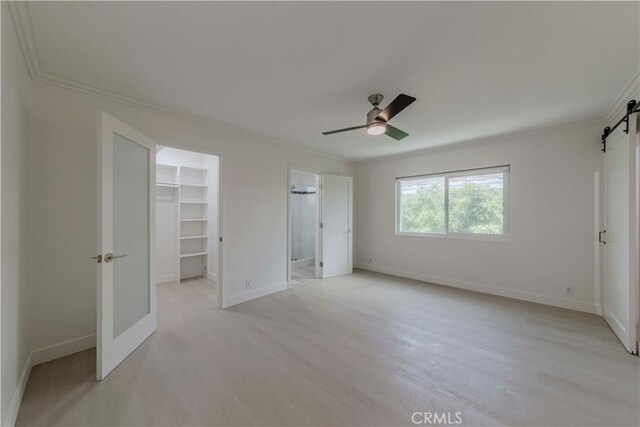 645 N Gramercy Pl, Los Angeles, CA 90004 - unfurnished bedroom featuring a barn door, ornamental molding, a walk in closet, a closet, and ceiling fan