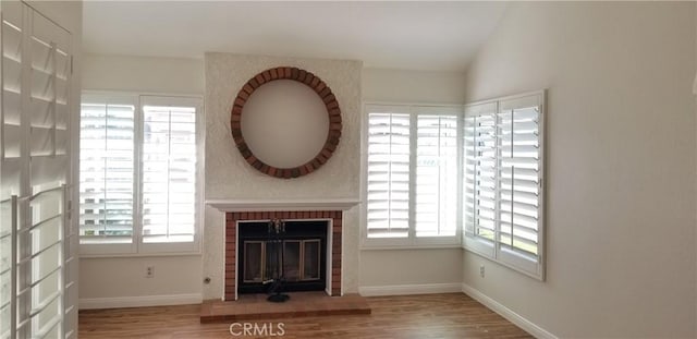 12180 Westerly Trl, Moreno Valley, CA 92557 - unfurnished living room featuring wood finished floors, healthy amount of natural light, a fireplace, and vaulted ceiling