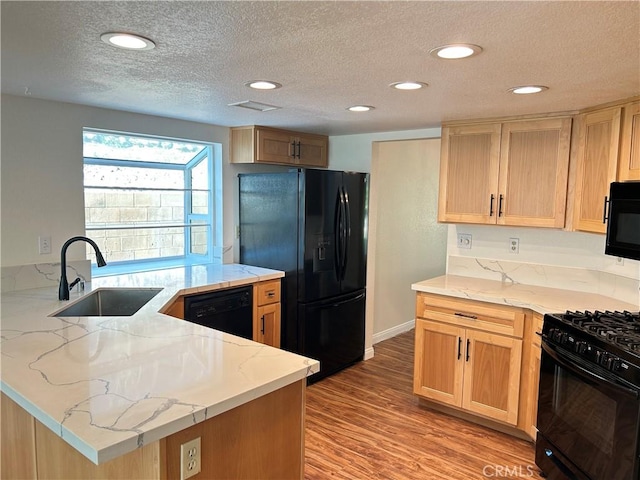 12180 Westerly Trl, Moreno Valley, CA 92557 - kitchen with black appliances, a textured ceiling, a peninsula, light stone counters, and light wood-style floors