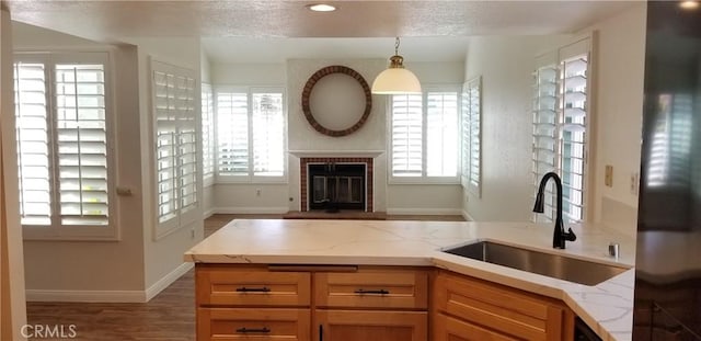 12180 Westerly Trl, Moreno Valley, CA 92557 - kitchen with light stone counters, a fireplace, pendant lighting, wood finished floors, and a textured ceiling