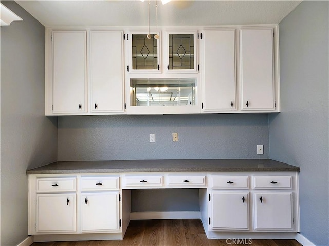 10201 Mason Ave Unit 34, Chatsworth, CA 91311 - kitchen featuring built in study area, white cabinetry, dark wood finished floors, and dark countertops