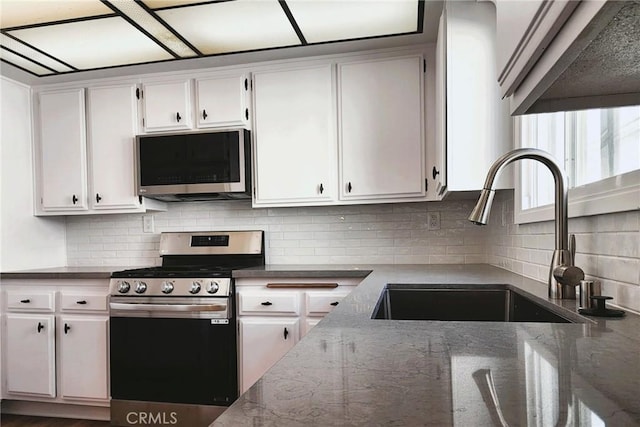 10201 Mason Ave Unit 34, Chatsworth, CA 91311 - kitchen with appliances with stainless steel finishes, backsplash, white cabinets, and dark stone counters