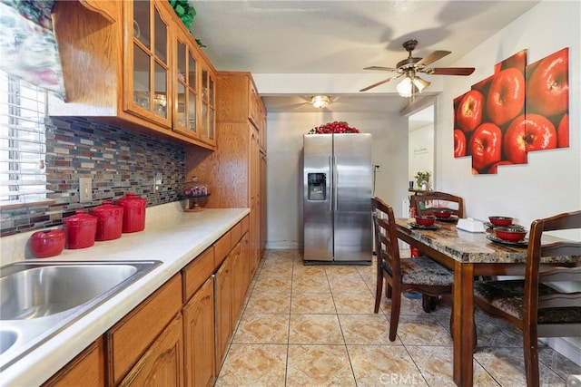 430 E 104th St, Los Angeles, CA 90003 - kitchen featuring brown cabinetry, stainless steel refrigerator with ice dispenser, backsplash, light countertops, and glass insert cabinets