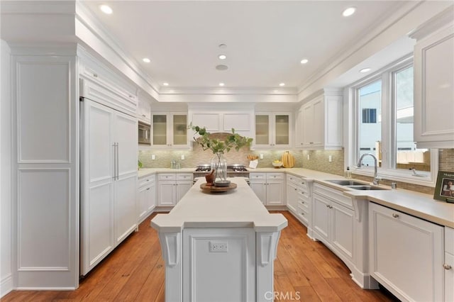 3201 4th Ave, Corona Del Mar, CA 92625 - kitchen featuring built in appliances, white cabinetry, light countertops, a kitchen island, and glass insert cabinets