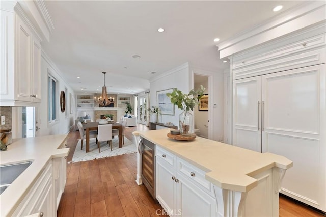 3201 4th Ave, Corona Del Mar, CA 92625 - kitchen featuring beverage cooler, white cabinetry, ornamental molding, recessed lighting, and hardwood / wood-style floors