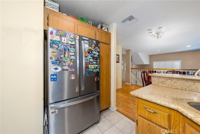 23220 Colony Park Dr, Carson, CA 90745 - kitchen with freestanding refrigerator, light tile patterned flooring, light stone countertops, and brown cabinets