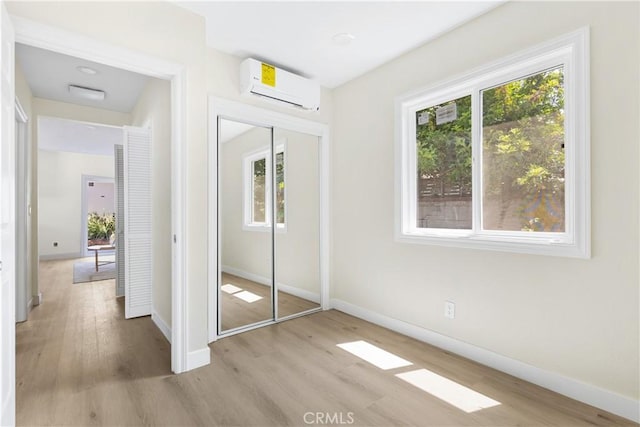 3876 Olmsted Ave, Los Angeles, CA 90008 - unfurnished bedroom featuring a wall unit AC, wood finished floors, and a closet