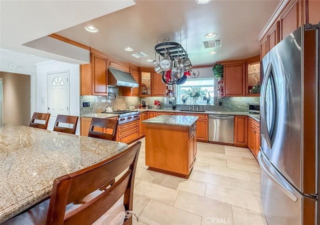 17213 Horace St, Granada Hills, CA 91344 - kitchen featuring appliances with stainless steel finishes, ventilation hood, tasteful backsplash, light stone counters, and a kitchen island