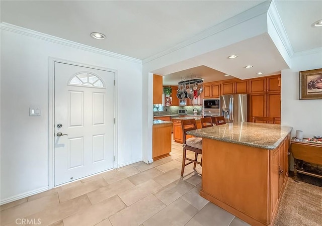 17213 Horace St, Granada Hills, CA 91344 - kitchen with stainless steel fridge, black microwave, brown cabinets, ornamental molding, and a kitchen bar