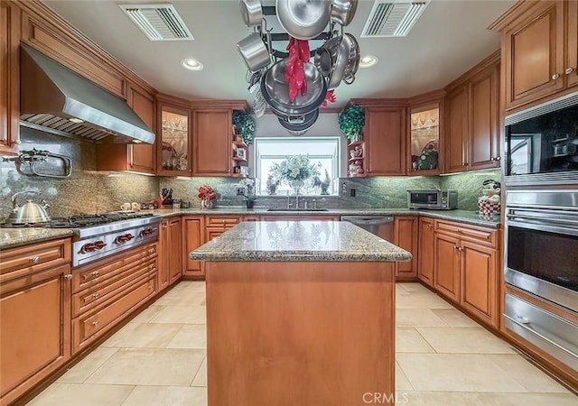 17213 Horace St, Granada Hills, CA 91344 - kitchen featuring stainless steel appliances, wall chimney exhaust hood, a warming drawer, a kitchen island, and brown cabinetry