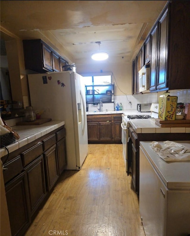 1239 W Rosecrans, Gardena, CA 90247 - kitchen featuring white appliances, light wood-style flooring, dark brown cabinetry, and tile counters